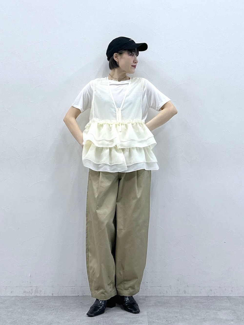 ベージュ系のチノパンツ、ホワイト系のTシャツ/カットソー、ホワイト系のベストを着用したレディースの春コーディネートの2枚目の写真