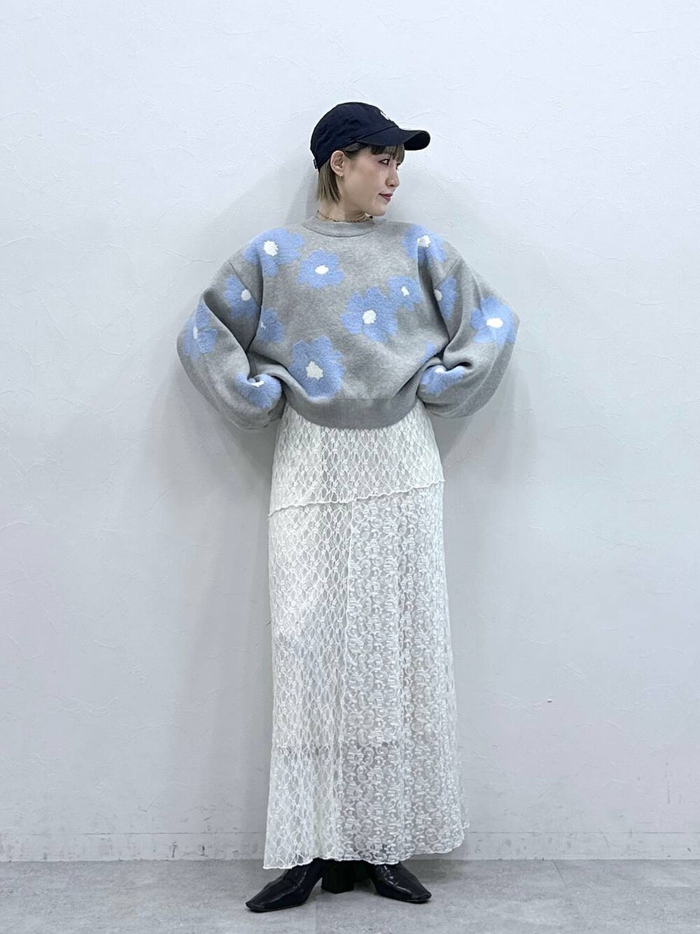 グレー系のニット/セーター、ホワイト系のスカートを着用したレディースの冬コーディネートの2枚目の写真