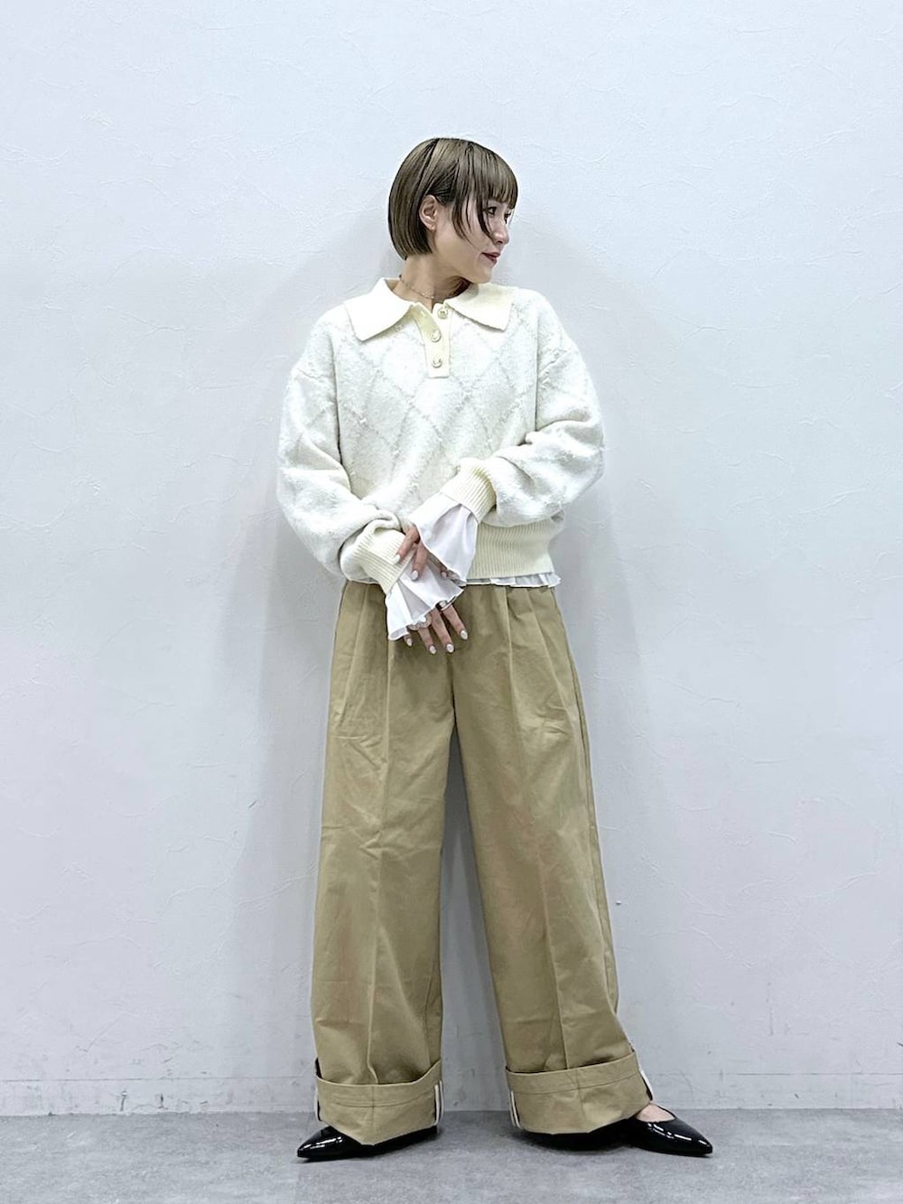 ブラック系のパンプス、ホワイト系のTシャツ/カットソー、ベージュ系のチノパンツを着用したレディースの冬コーディネートの3枚目の写真