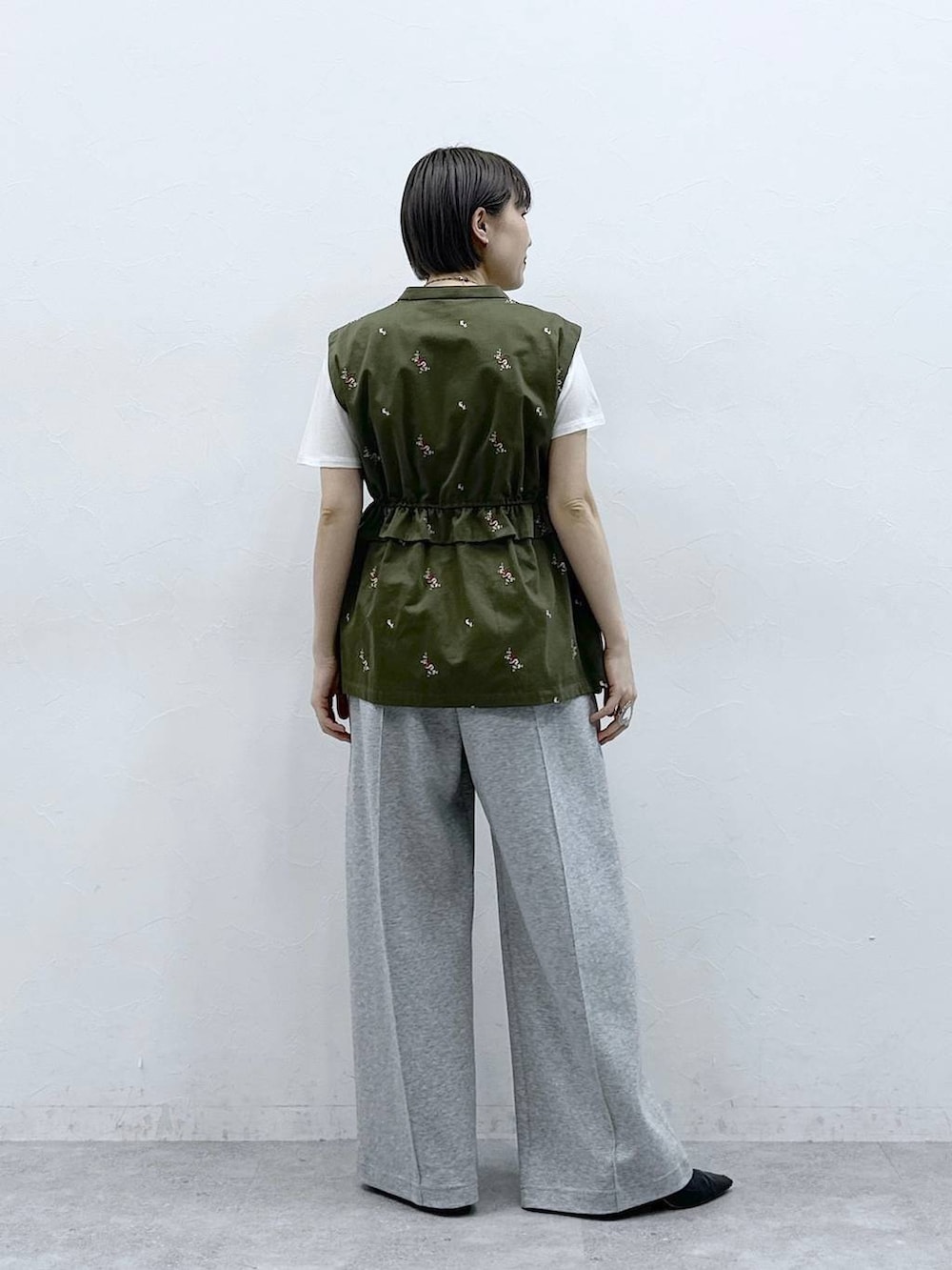 グレー系のスウェットパンツ、ホワイト系のTシャツ/カットソー、グリーン系のベストを着用したレディースの春コーディネートの5枚目の写真