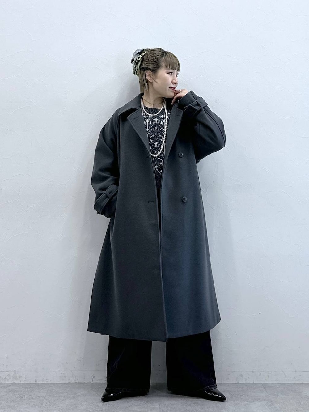 グレー系のステンカラーコート、ブラック系のニット/セーター、ブラック系のパンプスを着用したレディースの冬コーディネートの2枚目の写真