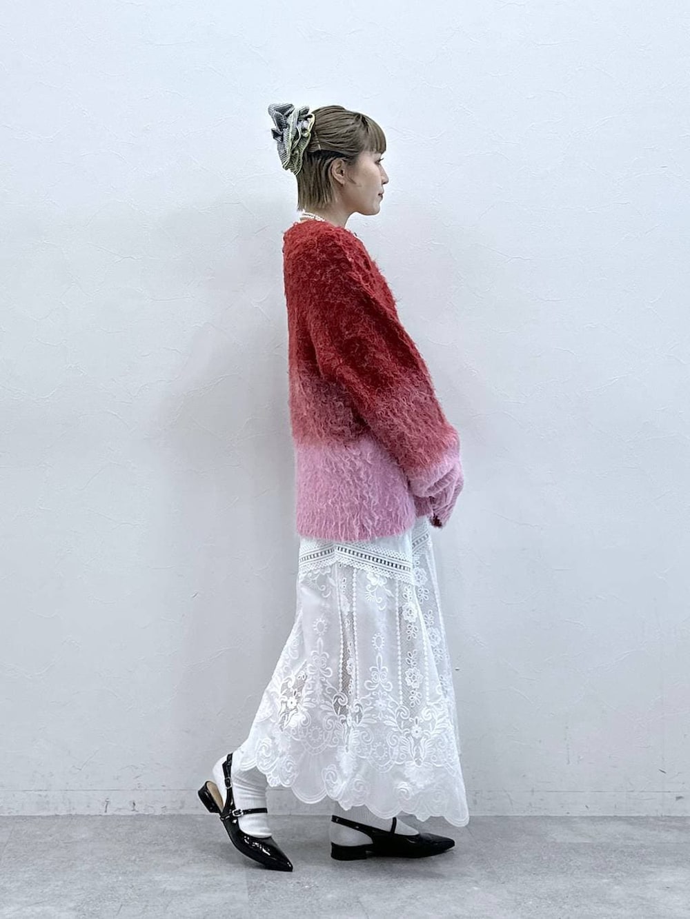 ホワイト系のスカート、レッド系のニット/セーター、ブラック系のパンプスを着用したレディースの冬コーディネートの4枚目の写真