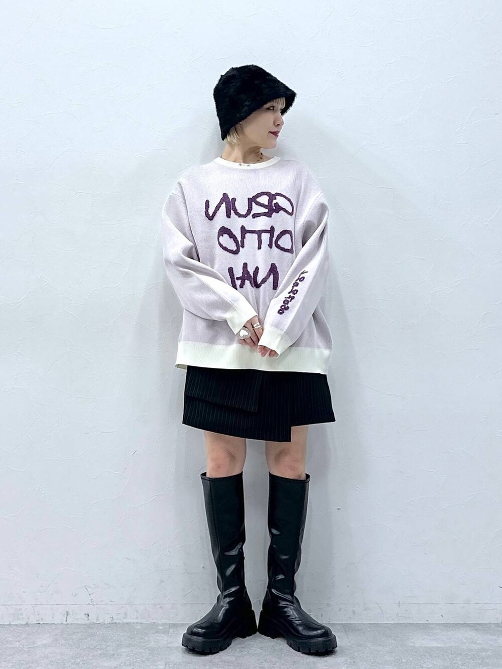 ブラック系のブーツ、ホワイト系のニット/セーター、ブラック系のスカートを着用したレディースの秋コーディネートの2枚目の写真