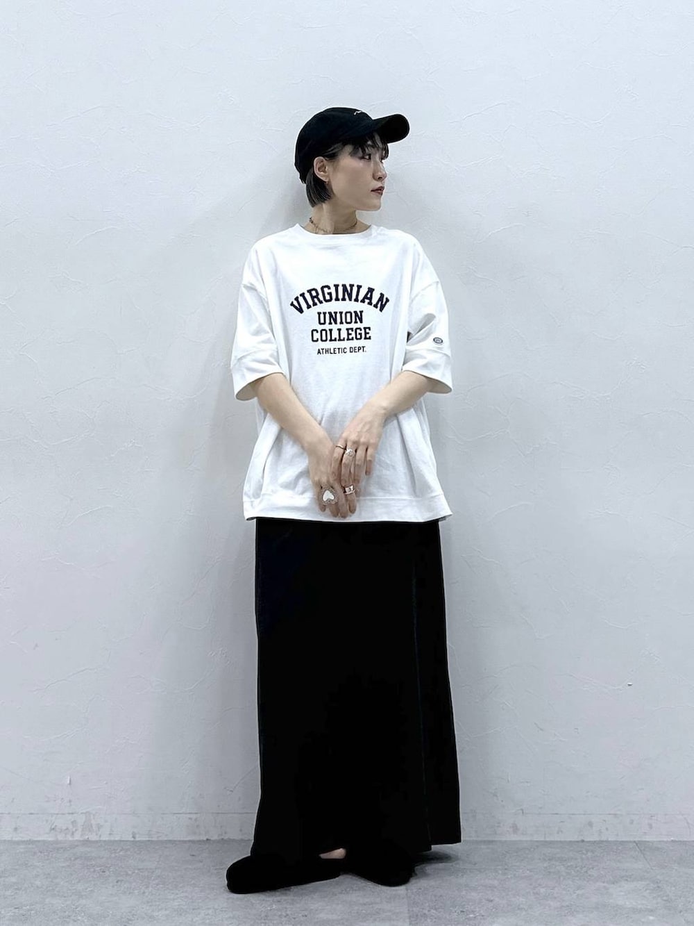 ホワイト系のTシャツ/カットソー、ブラック系のモカシン/デッキシューズ、ブラック系のスカートを着用したレディースの春コーディネートの2枚目の写真