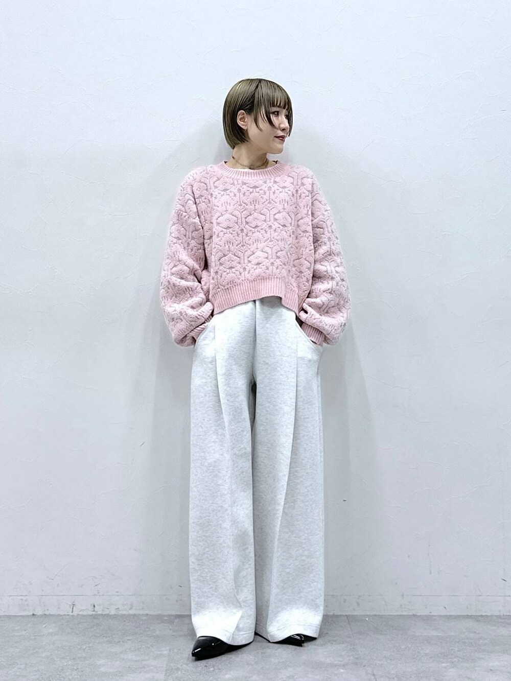 ホワイト系のTシャツ/カットソー、ブラック系のパンプス、ピンク系のニット/セーターを着用したレディースの冬コーディネートの2枚目の写真