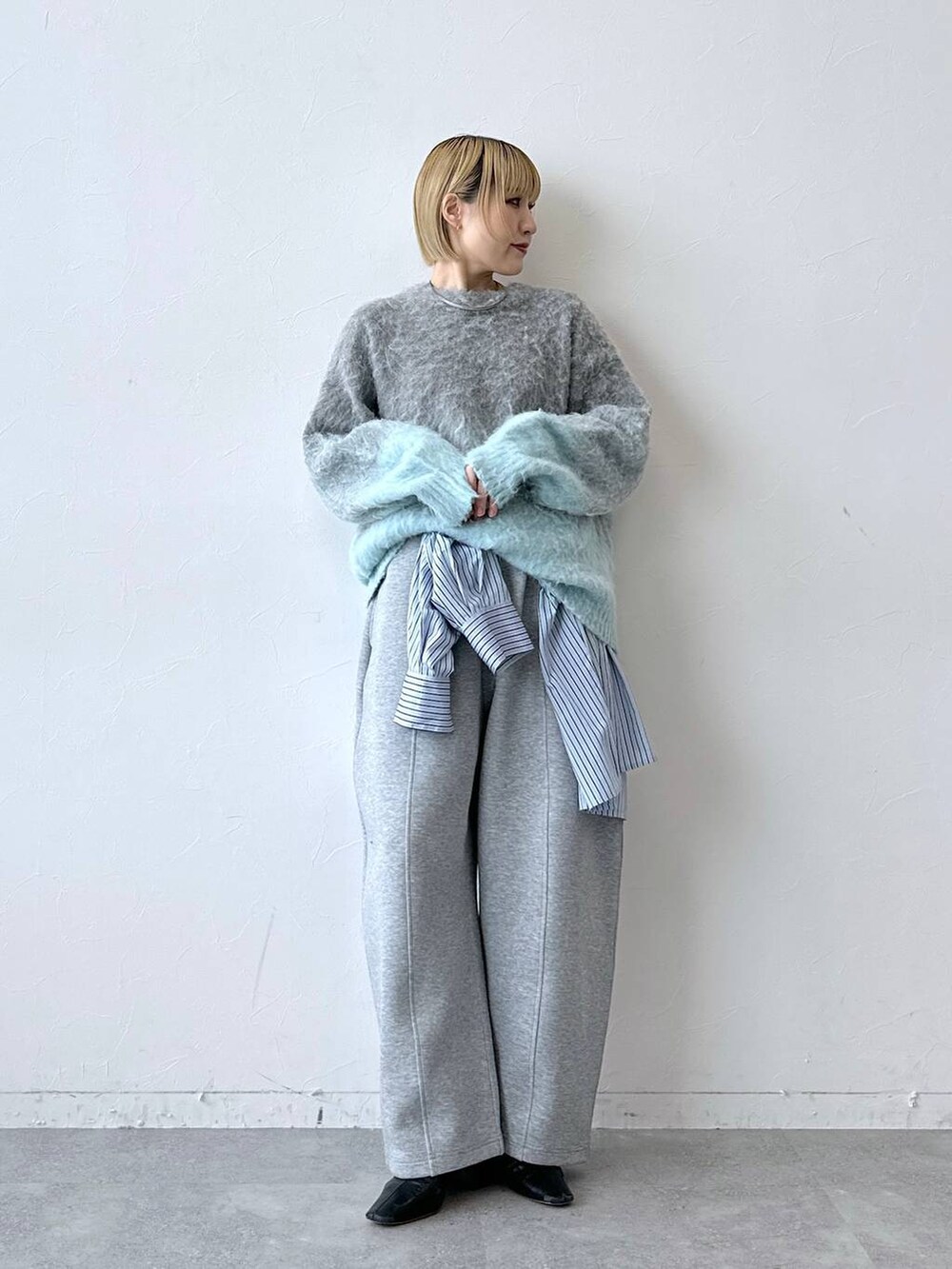 グレー系のニット/セーター、ブルー系のTシャツ/カットソー、グレー系のスウェットパンツを着用したレディースの秋コーディネートの5枚目の写真