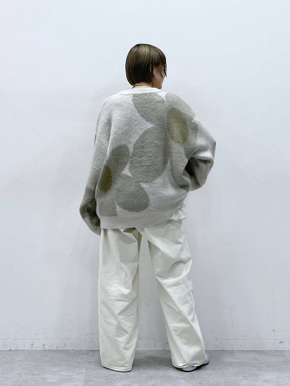 ホワイト系のニット/セーター、ホワイト系のキャミソール、ホワイト系のチノパンツを着用したレディースの冬コーディネートの5枚目の写真