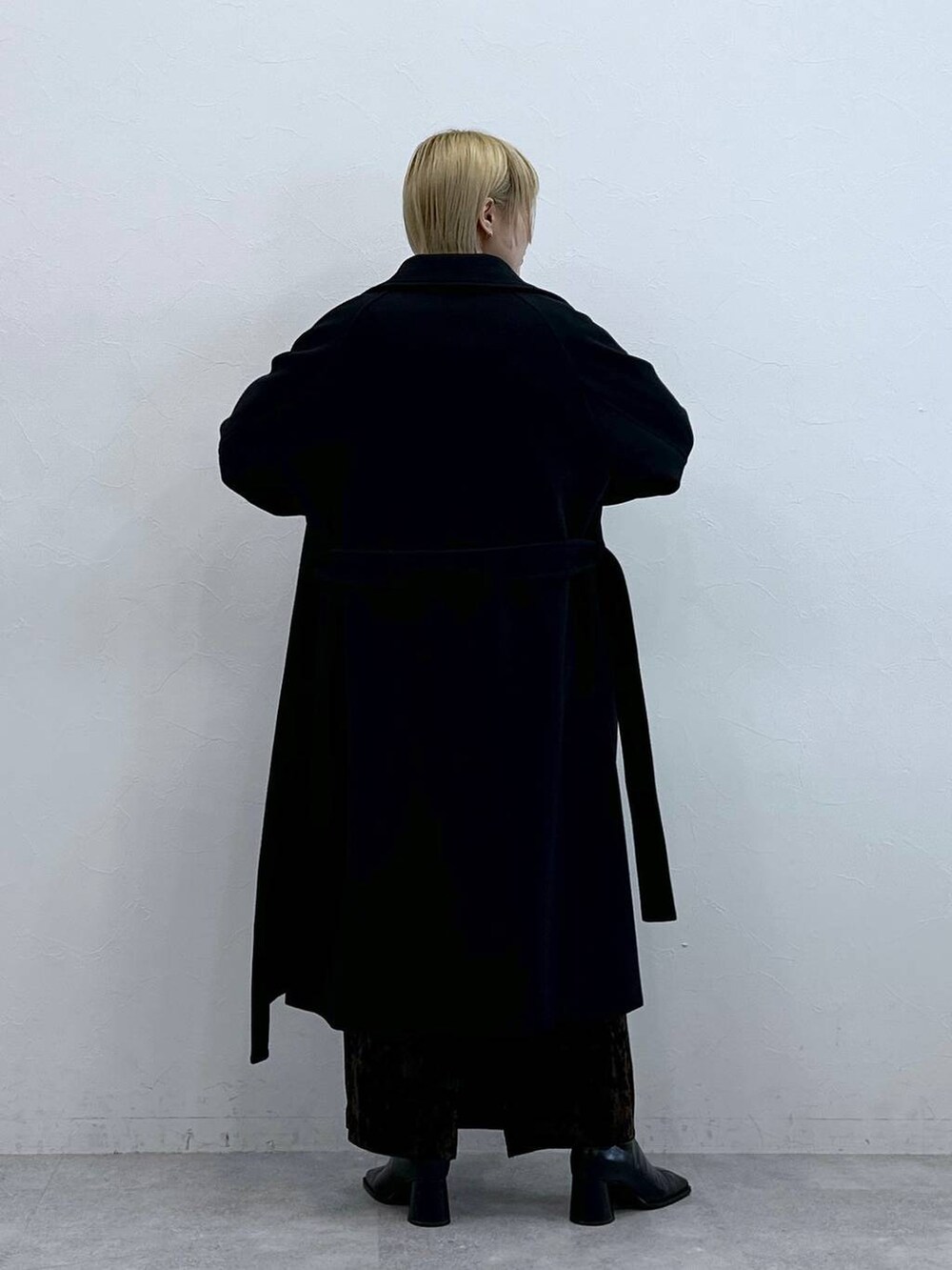 ブラック系のステンカラーコート、ホワイト系のTシャツ/カットソー、ブラック系のスカートを着用したレディースの秋コーディネートの5枚目の写真