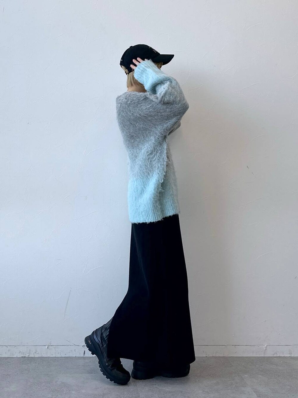 グレー系のニット/セーター、ブラック系のスカート、ブラック系のキャップを着用したレディースの秋コーディネートの5枚目の写真