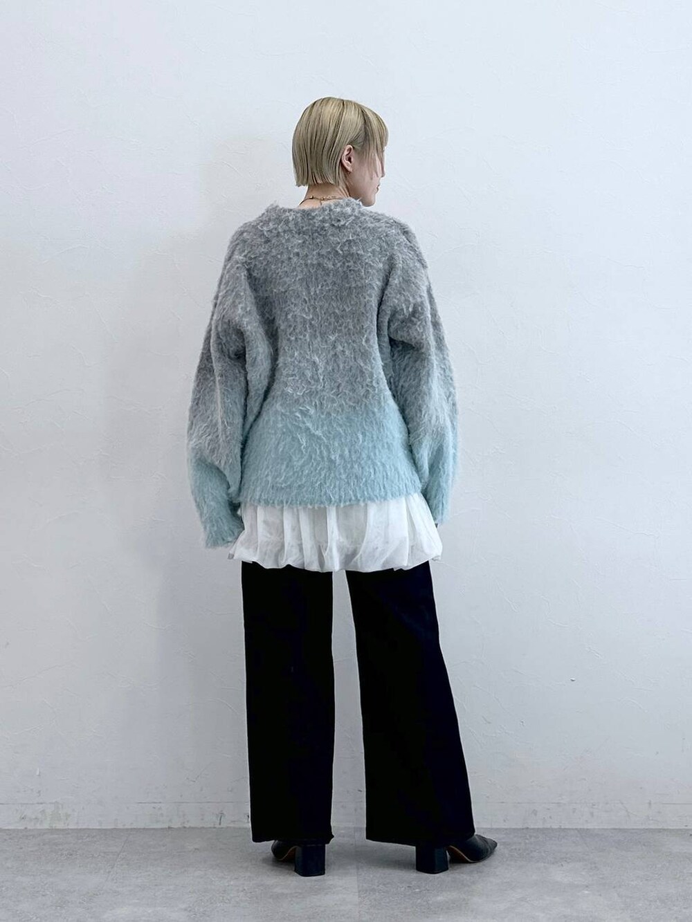 ブラック系のデニムパンツ、ホワイト系のスカート、グレー系のニット/セーターを着用したレディースの秋コーディネートの5枚目の写真