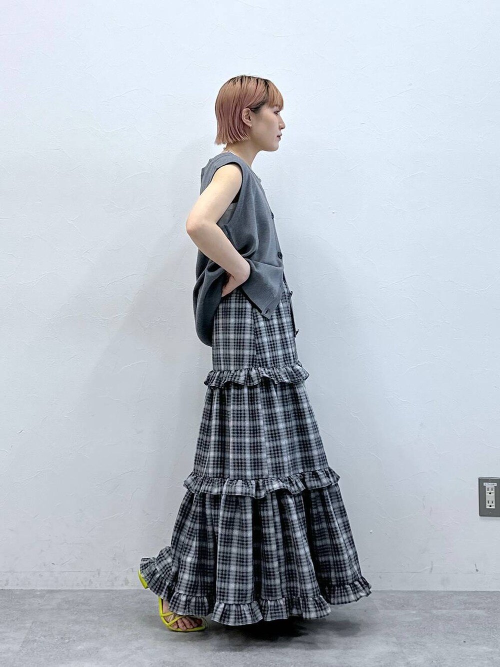 グレー系のベスト、ホワイト系のタンクトップ、ブラック系のスカートを着用したレディースの春コーディネートの5枚目の写真