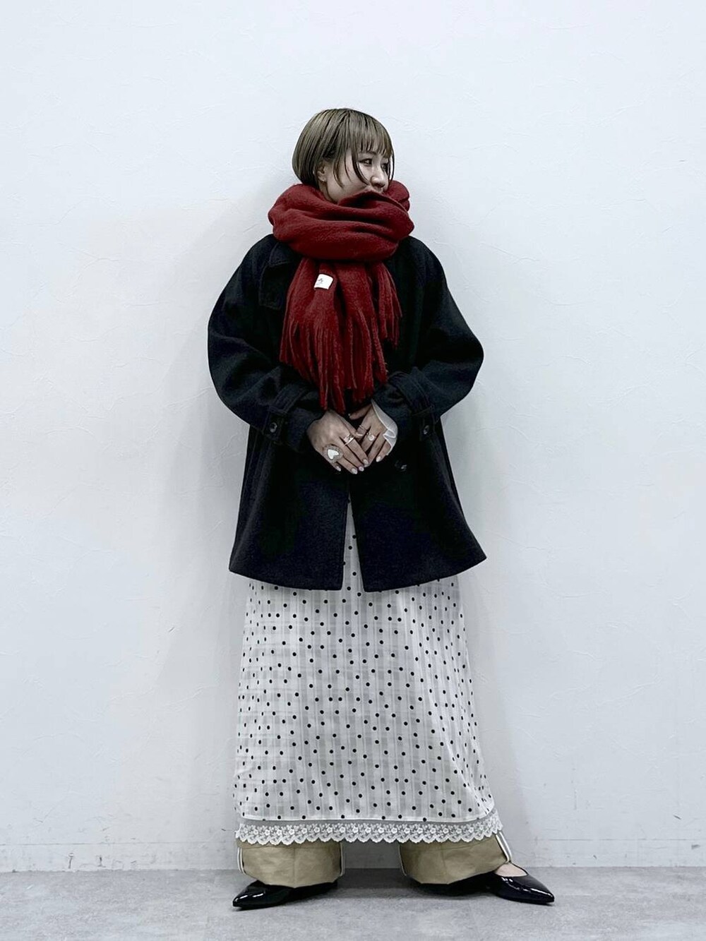 ブラック系のパンプス、ブラック系のステンカラーコート、ベージュ系のチノパンツを着用したレディースの冬コーディネートの4枚目の写真