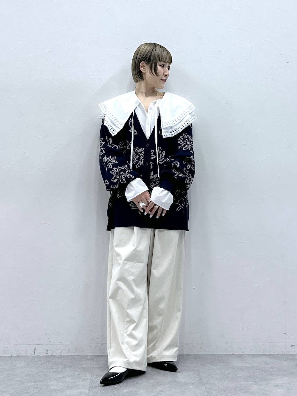 ホワイト系のチノパンツ、ホワイト系のシャツ/ブラウス、ブルー系のニット/セーターを着用したレディースの冬コーディネートの3枚目の写真