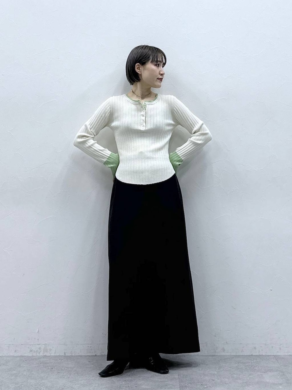 ブラック系のスカート、ホワイト系のニット/セーターを着用したレディースの春コーディネートの2枚目の写真