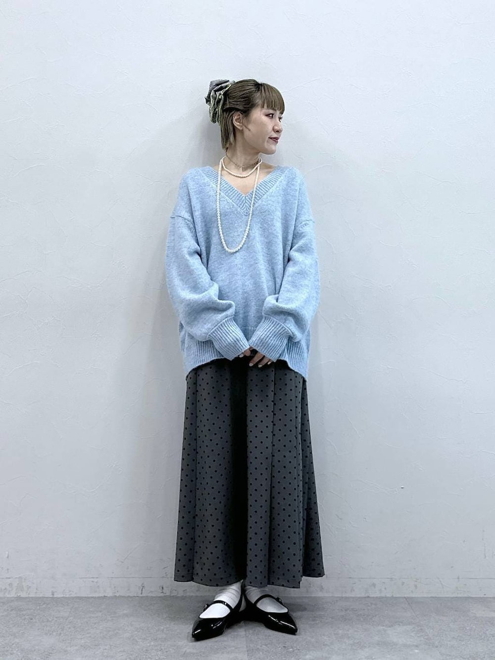 ブラック系のパンプス、ブルー系のニット/セーター、グレー系のスカートを着用したレディースの冬コーディネートの3枚目の写真