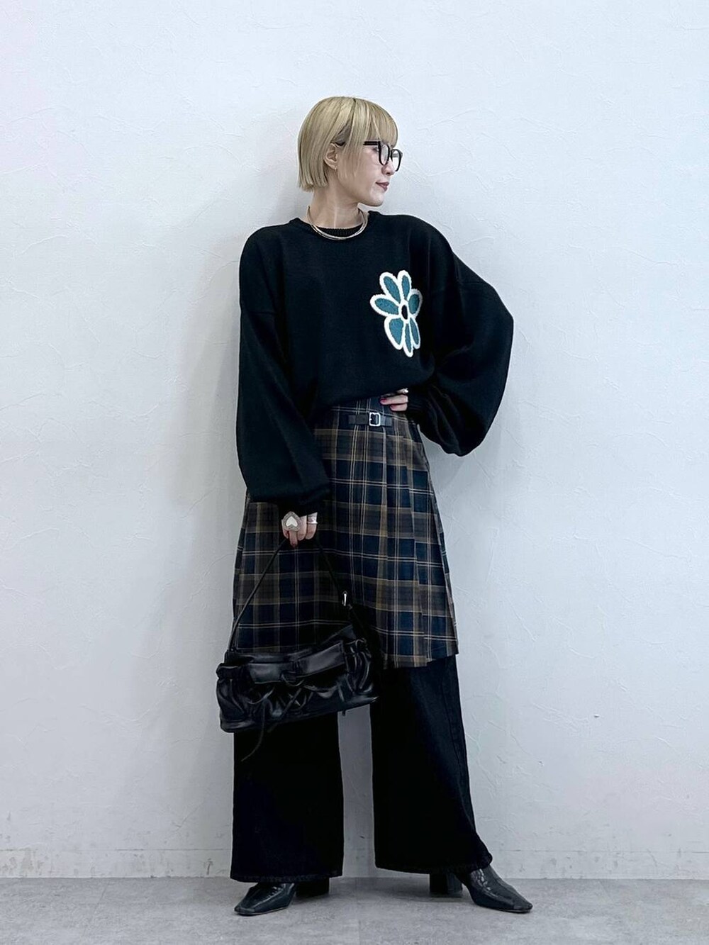 ブラック系のニット/セーター、ブラック系のデニムパンツ、ブラウン系のスカートを着用したレディースの秋コーディネートの2枚目の写真