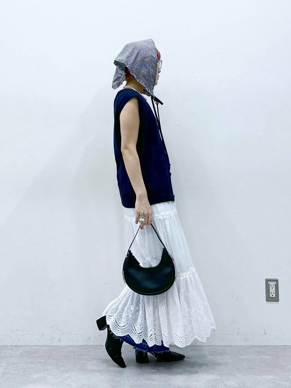 ブルー系のデニムパンツ、ブルー系のベスト、ホワイト系のタンクトップを着用したレディースの春コーディネートの5枚目の写真