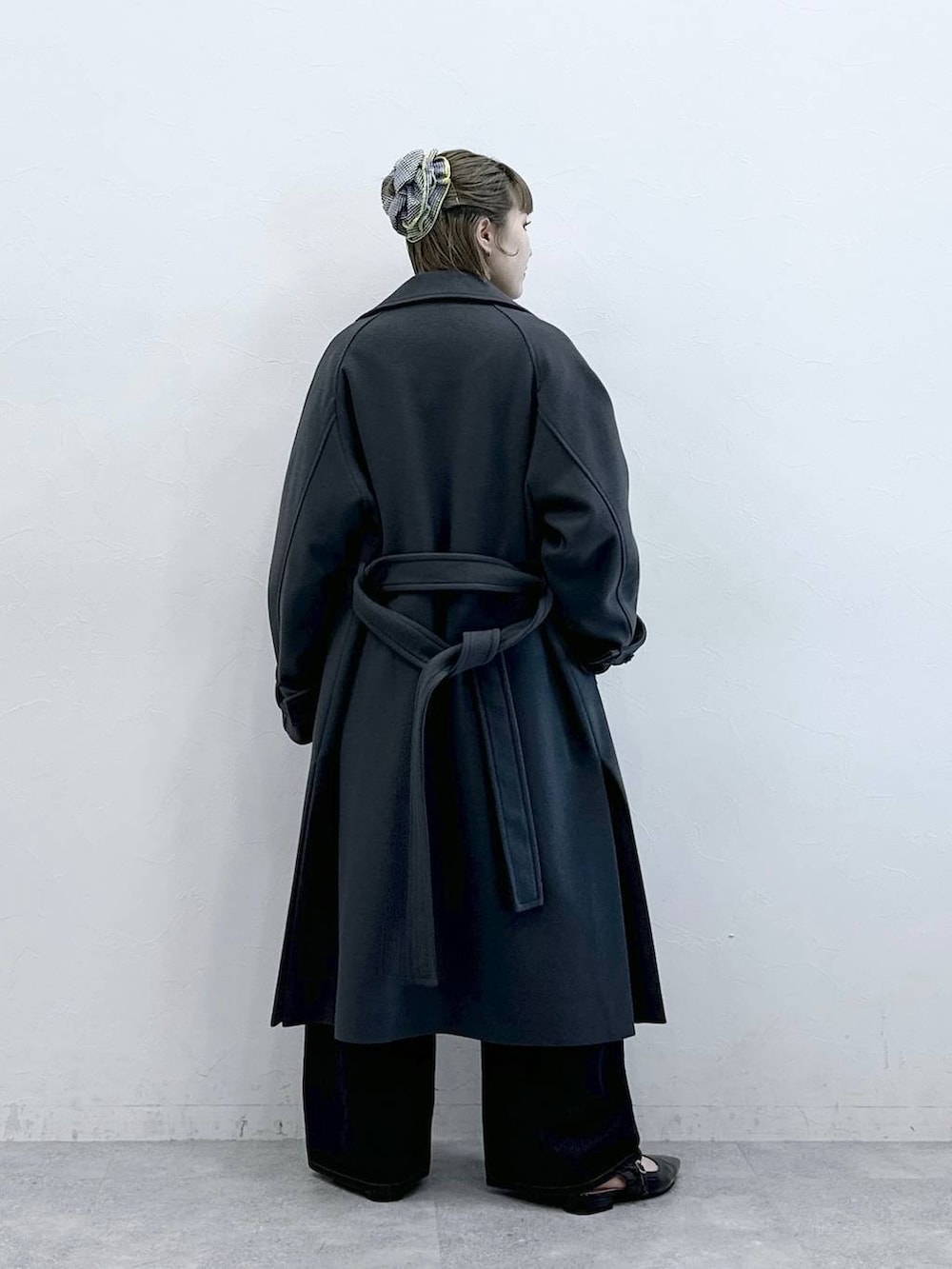 グレー系のステンカラーコート、ブラック系のニット/セーター、ブラック系のパンプスを着用したレディースの冬コーディネートの7枚目の写真