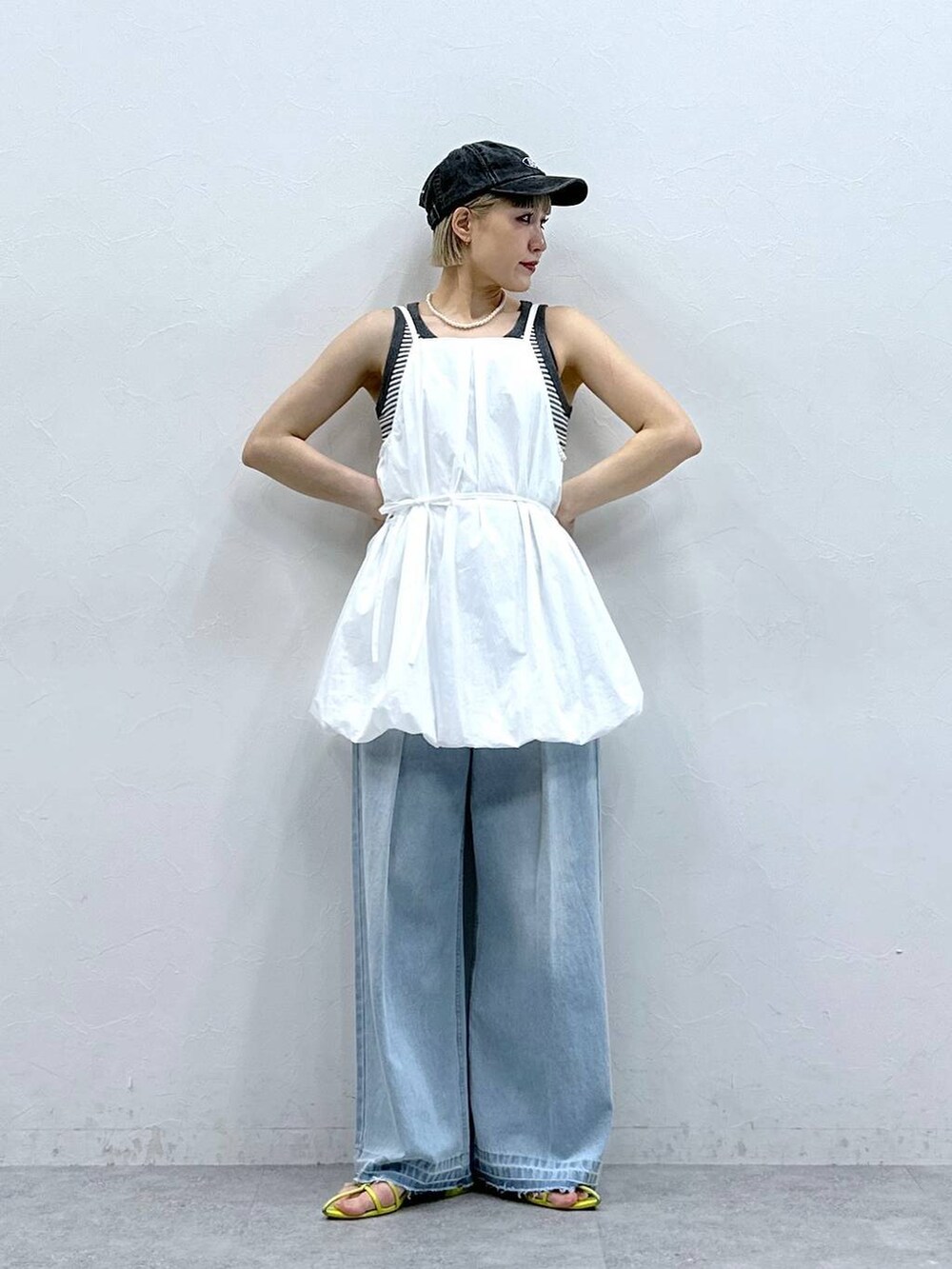 グレー系のタンクトップ、ブルー系のデニムパンツ、ホワイト系のワンピースを着用したレディースの夏コーディネートの5枚目の写真