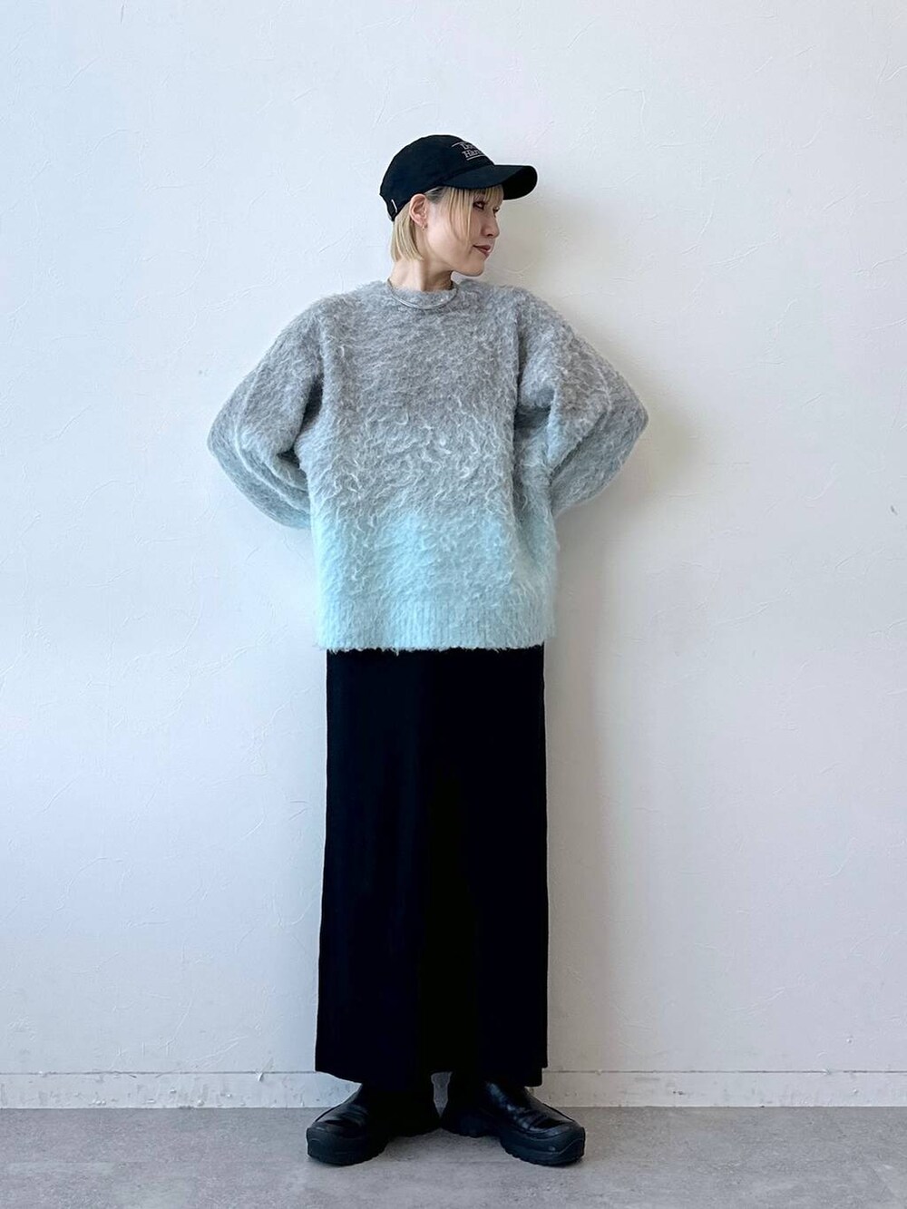 グレー系のニット/セーター、ブラック系のスカート、ブラック系のキャップを着用したレディースの秋コーディネートの3枚目の写真