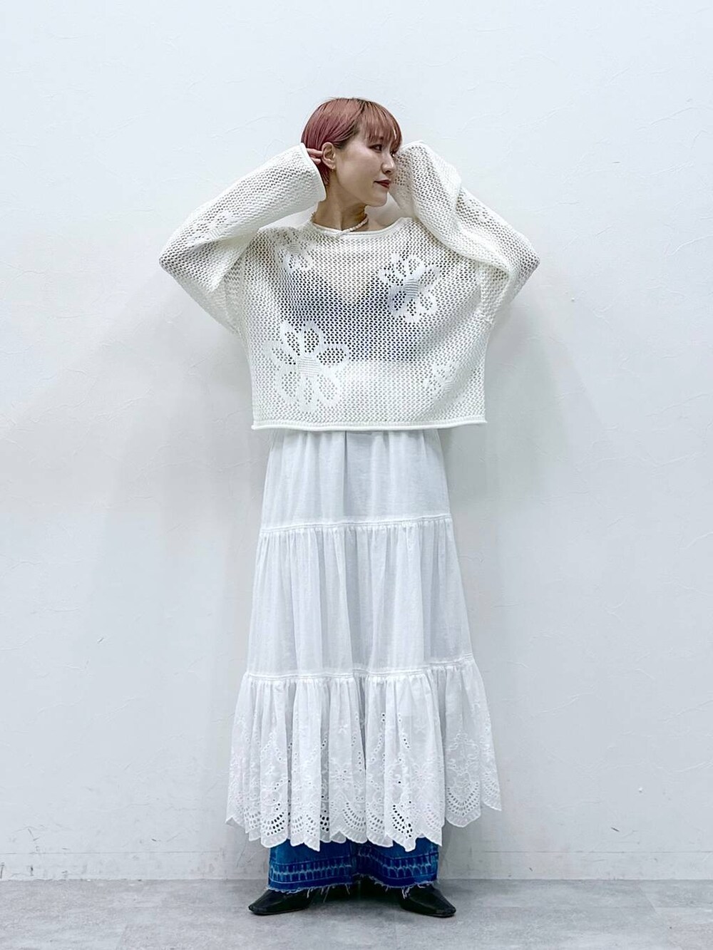 ブルー系のデニムパンツ、ホワイト系のニット/セーター、ホワイト系のスカートを着用したレディースの春コーディネートの2枚目の写真