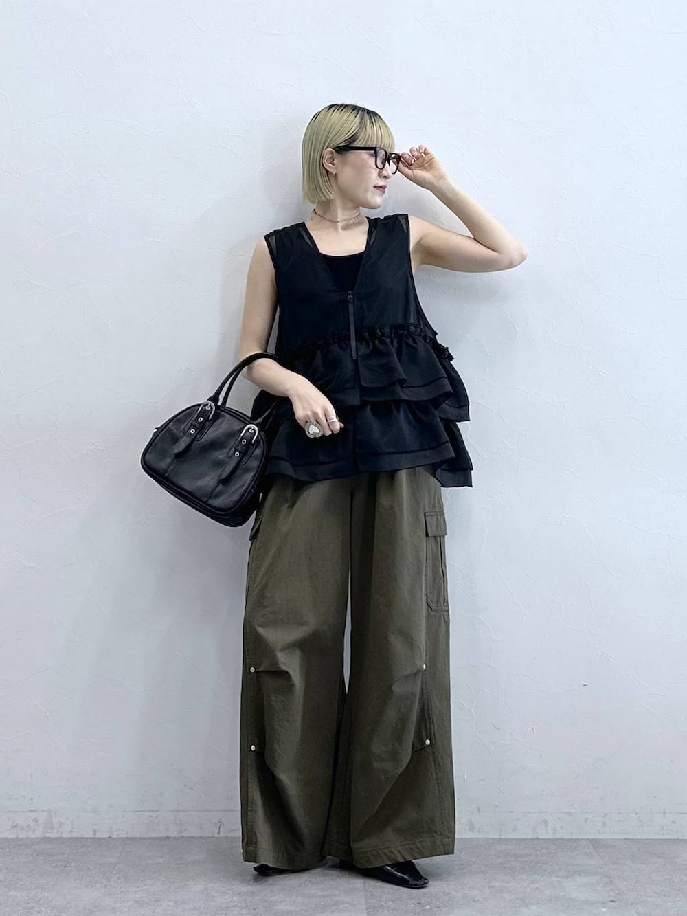 グリーン系のカーゴパンツ、ブラック系のタンクトップ、ブラック系のボストンバッグを着用したレディースの夏コーディネートの3枚目の写真