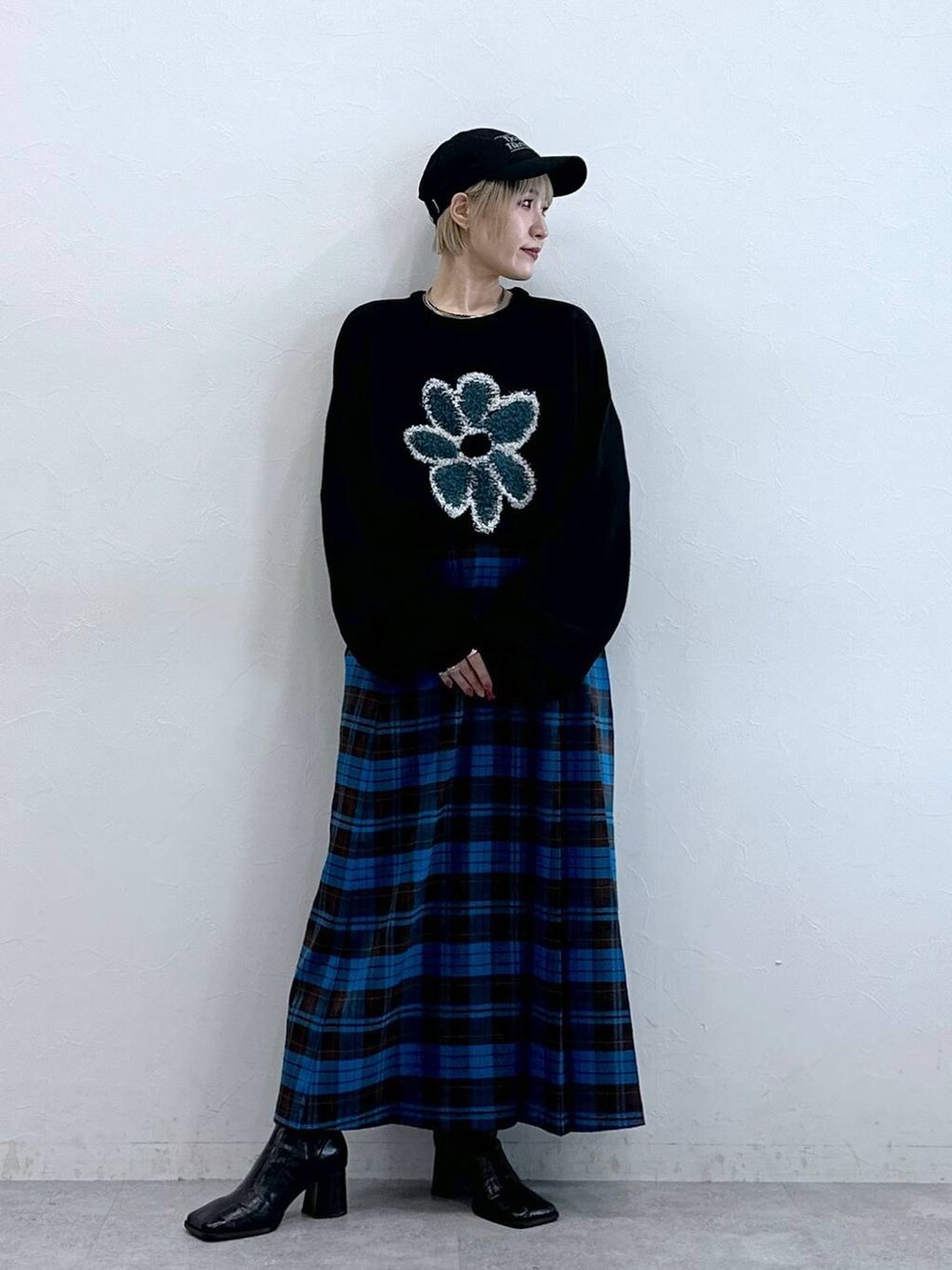 ブラック系のニット/セーター、ブルー系のスカート、ブラック系のキャップを着用したレディースの秋コーディネートの3枚目の写真