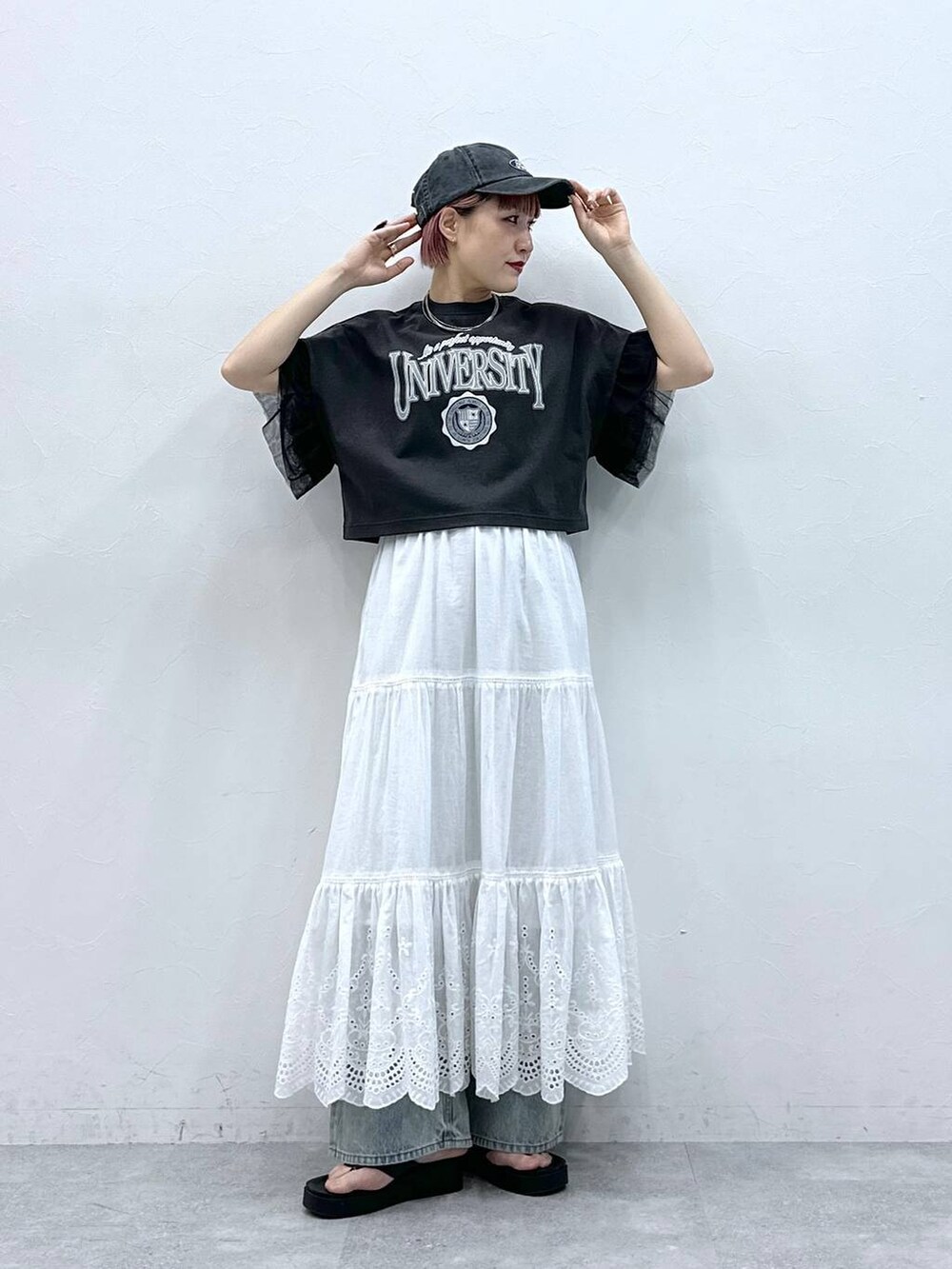 ブルー系のデニムパンツ、ブラック系のTシャツ/カットソー、ホワイト系のスカートを着用したレディースの春コーディネートの3枚目の写真
