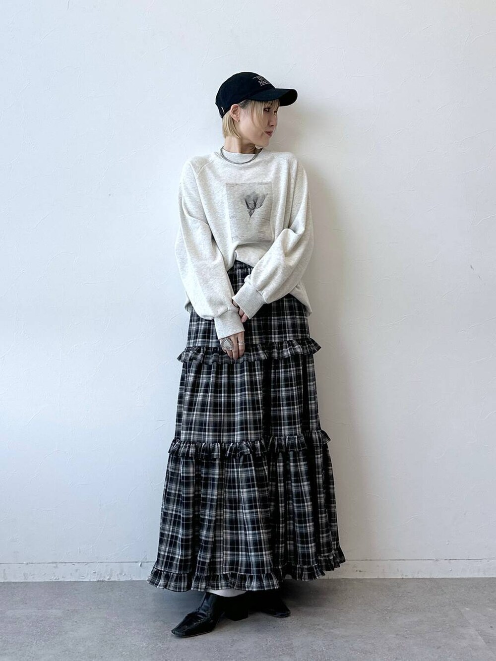 ホワイト系のスウェット、ブラック系のスカート、ブラック系のキャップを着用したレディースの秋コーディネートの3枚目の写真