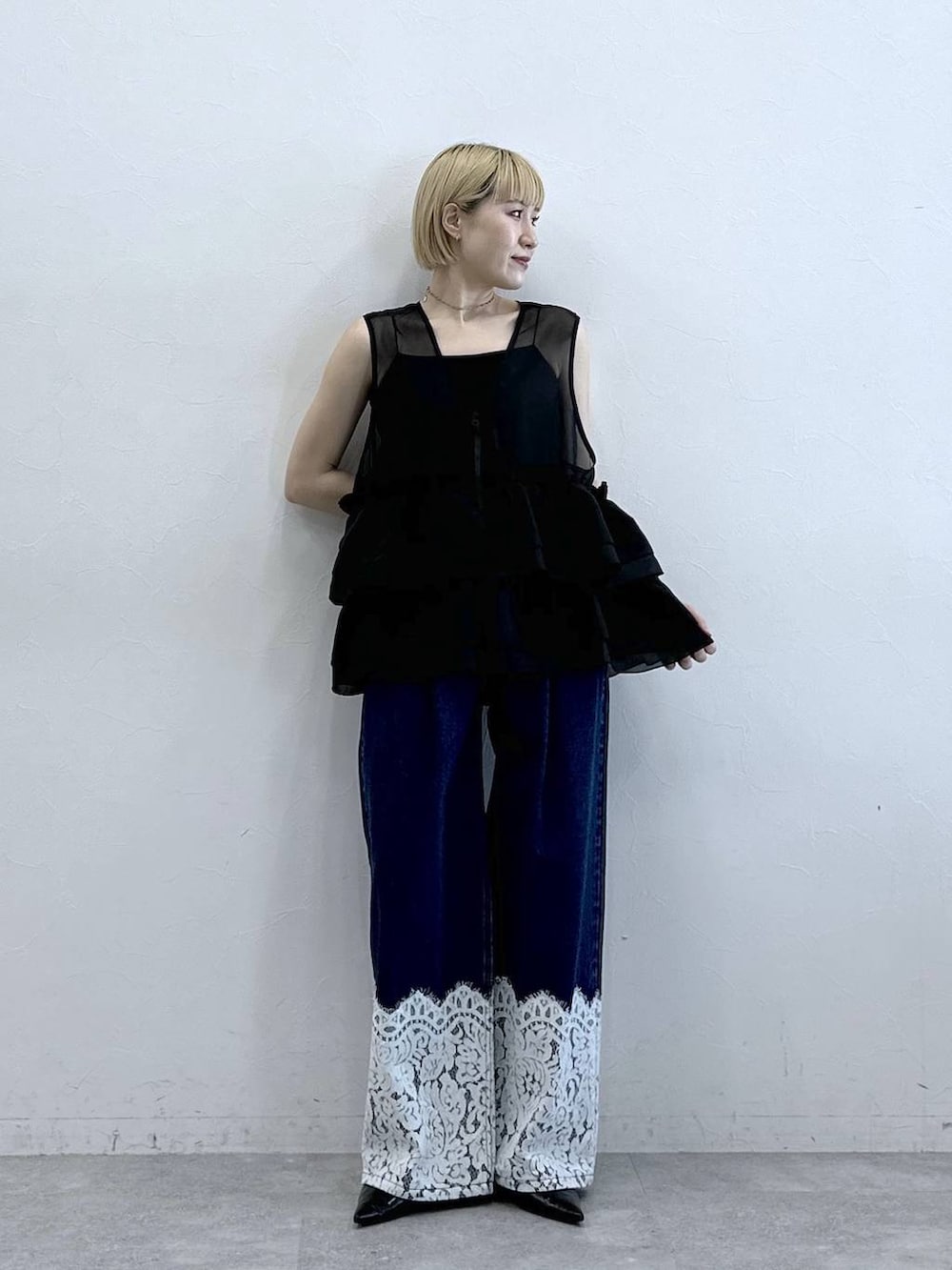 ブルー系のデニムパンツ、ブラック系のベスト、ブラック系のキャミソールを着用したレディースの春コーディネートの4枚目の写真