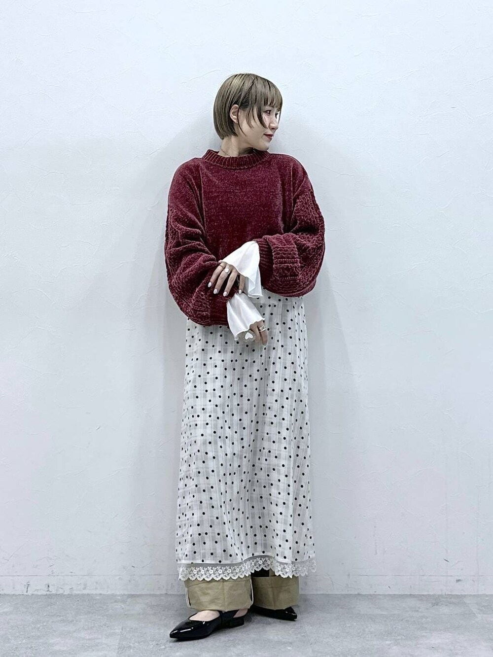 レッド系のニット/セーター、ブラック系のパンプス、ベージュ系のチノパンツを着用したレディースの冬コーディネートの2枚目の写真