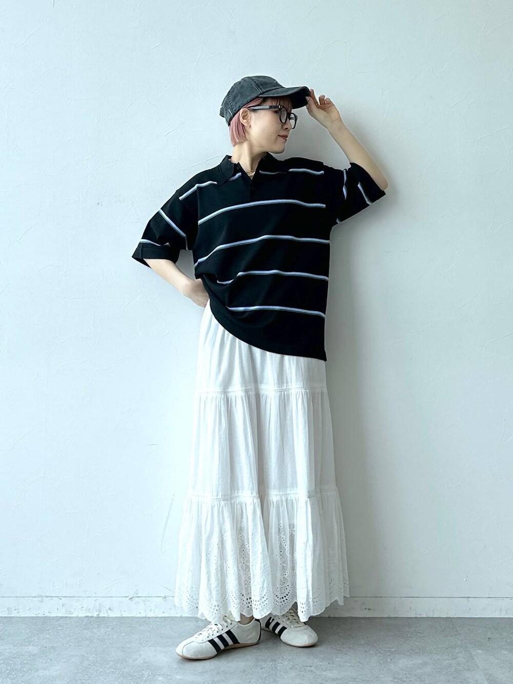 ホワイト系のスニーカー、ブラック系のポロシャツ、ホワイト系のスカートを着用したレディースの春コーディネートの2枚目の写真