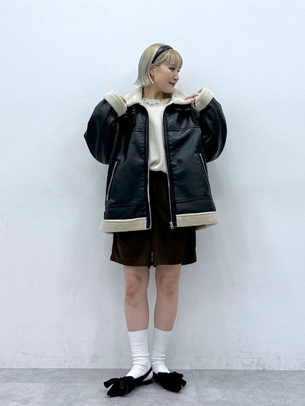 ブラック系のパンプス、ホワイト系のニット/セーター、ブラック系のムートンコートを着用したレディースの秋コーディネートの2枚目の写真