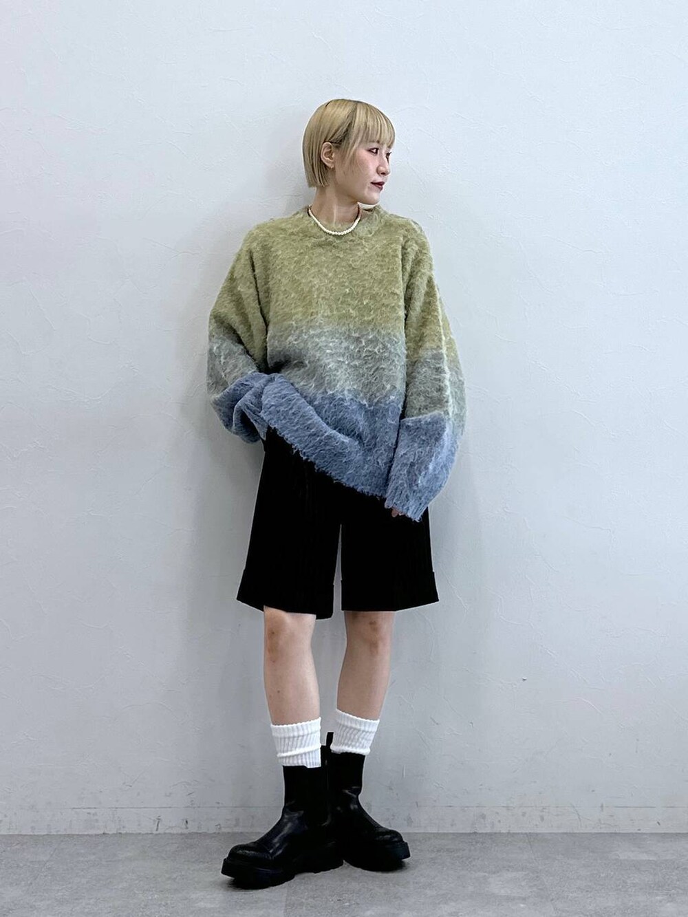 ブラウン系のスラックス、ブラック系のブーツ、イエロー系のニット/セーターを着用したレディースの秋コーディネートの4枚目の写真