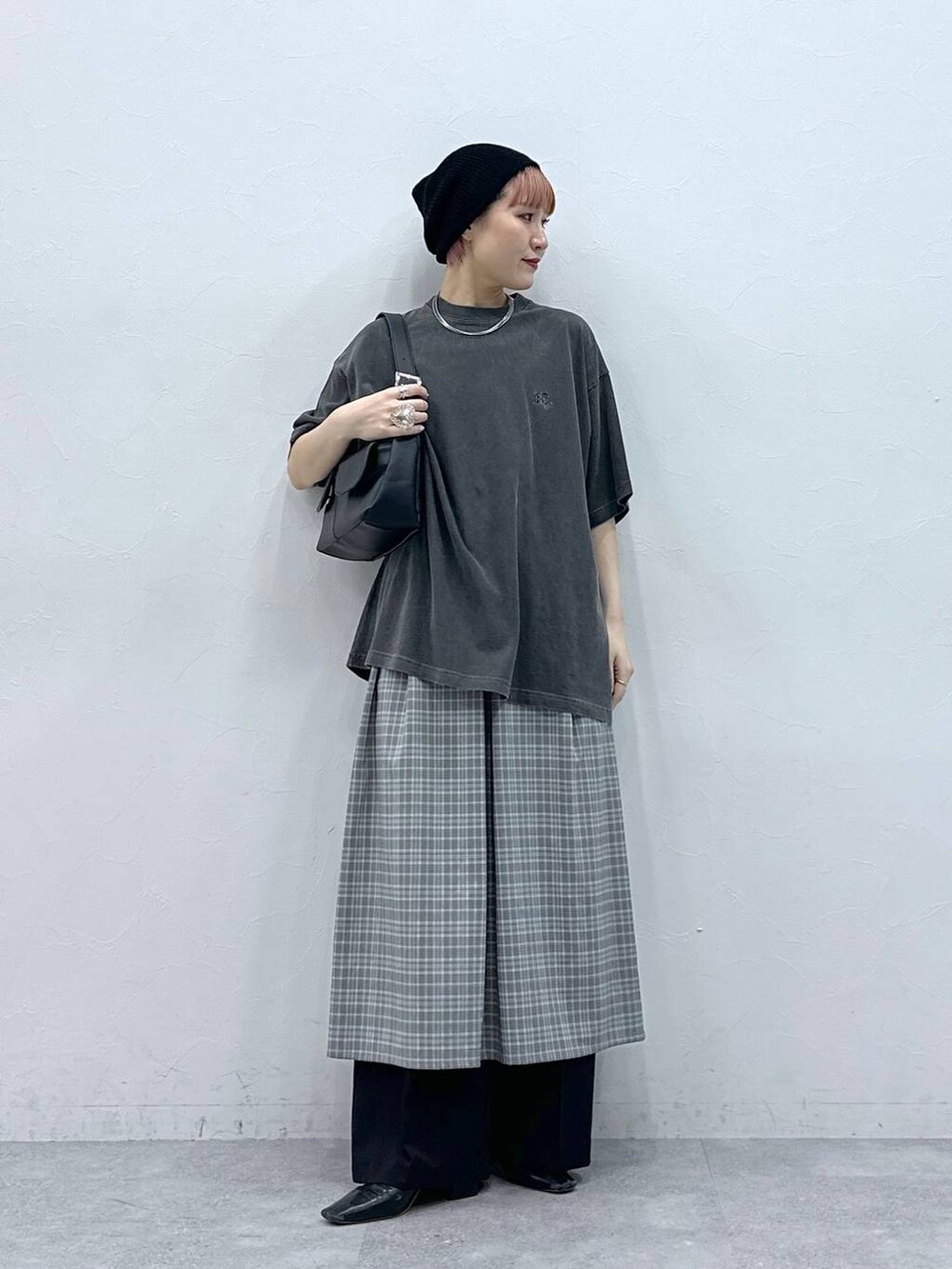 ブラック系のスラックス、グレー系のワンピース、ブラック系のTシャツ/カットソーを着用したレディースの春コーディネートの2枚目の写真