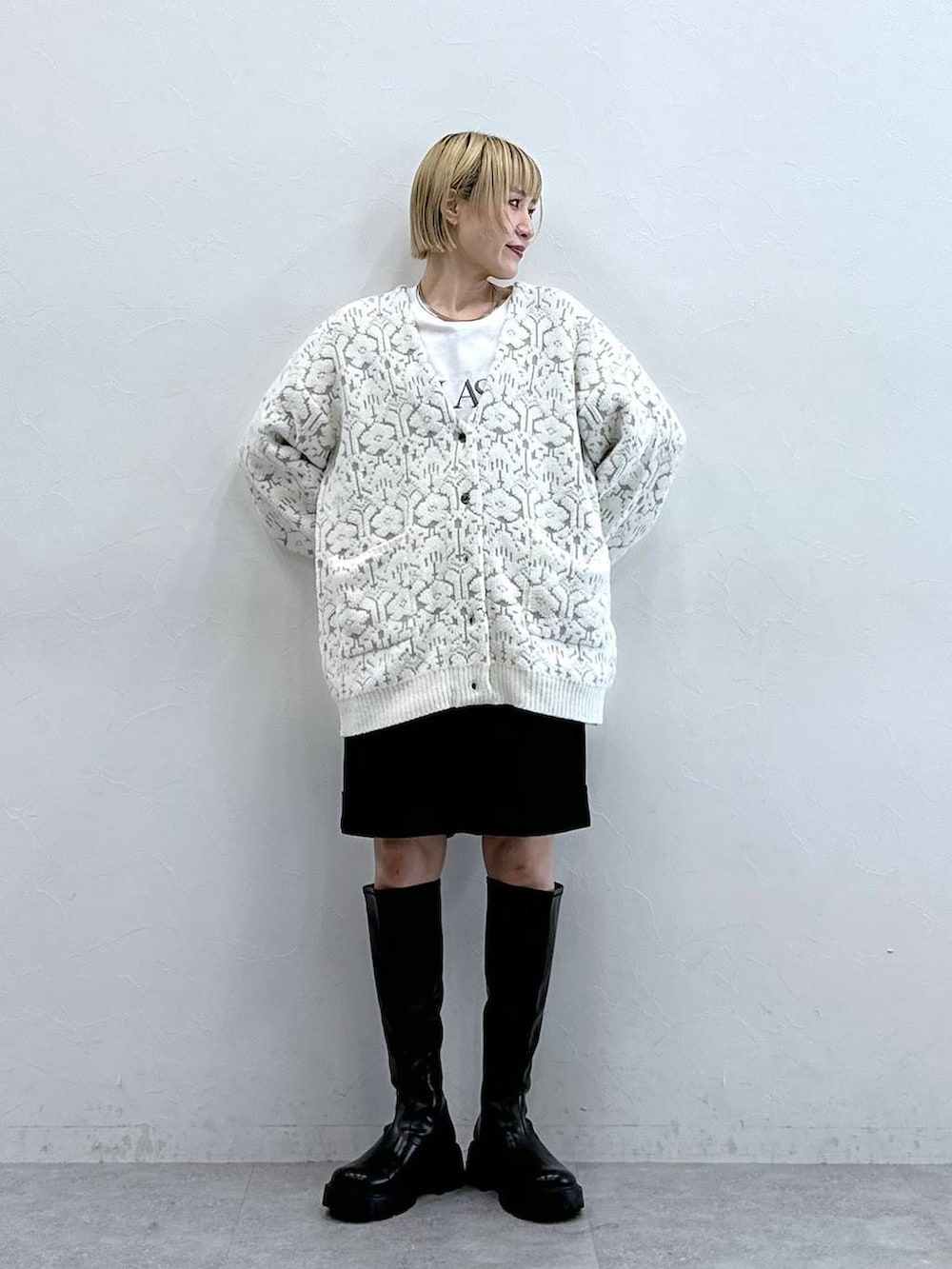 ブラック系のブーツ、ホワイト系のカーディガン/ボレロ、ブラック系のチノパンツを着用したレディースの秋コーディネートの2枚目の写真