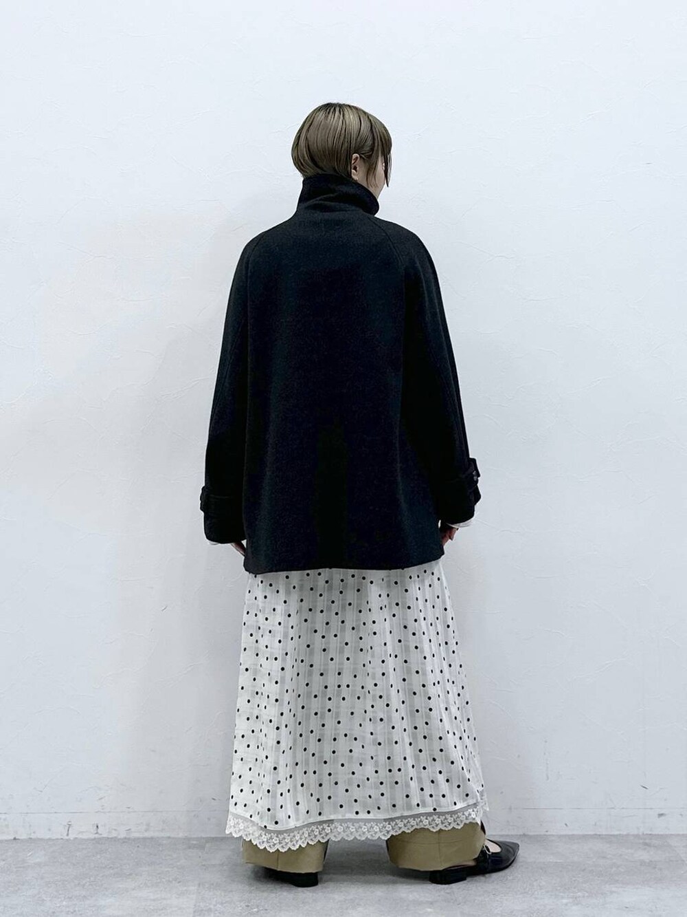 ブラック系のパンプス、ブラック系のステンカラーコート、ベージュ系のチノパンツを着用したレディースの冬コーディネートの7枚目の写真