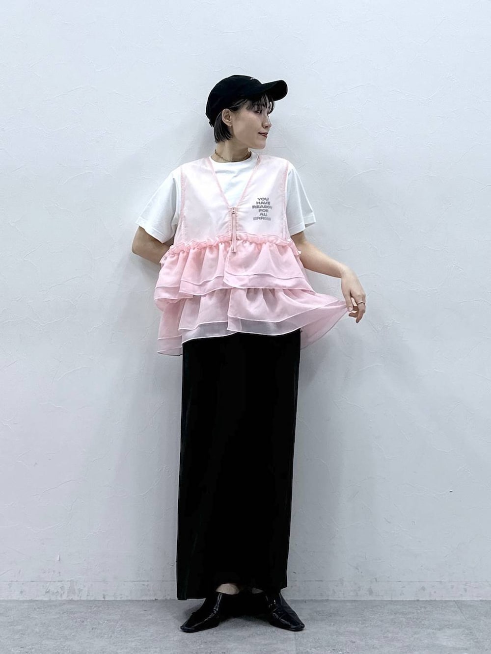 ブラック系のスカート、ホワイト系のTシャツ/カットソー、ピンク系のベストを着用したレディースの春コーディネートの2枚目の写真