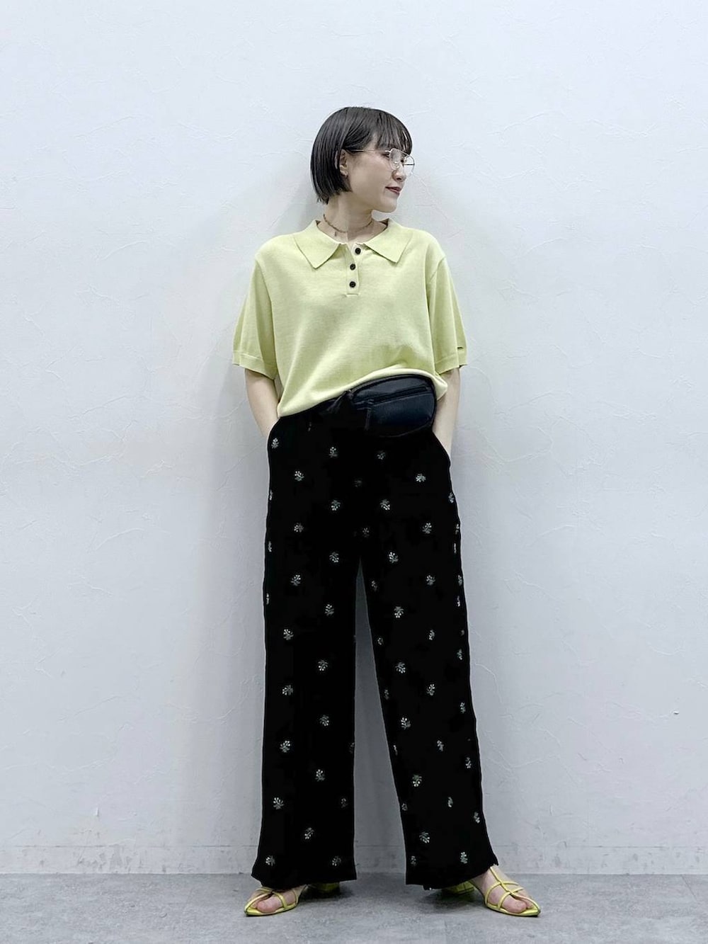 ブラック系のボディバッグ/ウエストポーチ、イエロー系のポロシャツ、ブラック系のスラックスを着用したレディースの春コーディネートの4枚目の写真