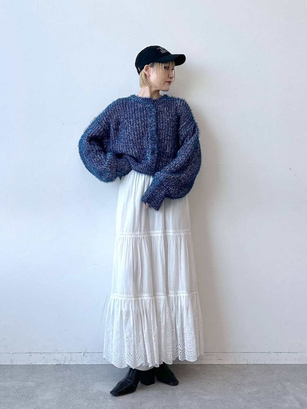 ブルー系のニット/セーター、ホワイト系のスカート、ブラック系のキャップを着用したレディースの秋コーディネートの3枚目の写真