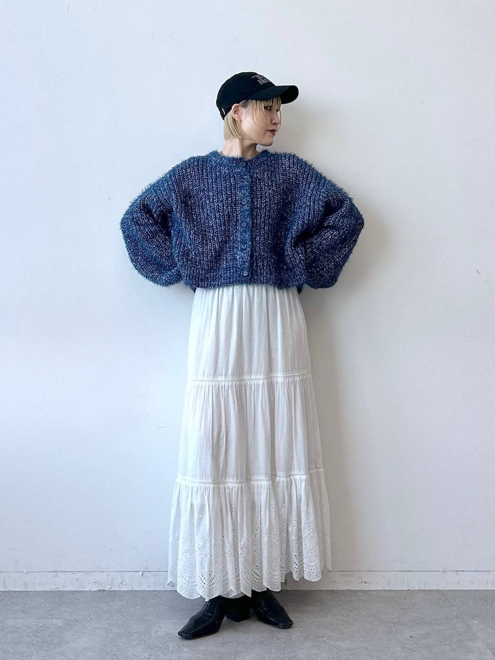 ブルー系のニット/セーター、ホワイト系のスカート、ブラック系のキャップを着用したレディースの秋コーディネートの4枚目の写真