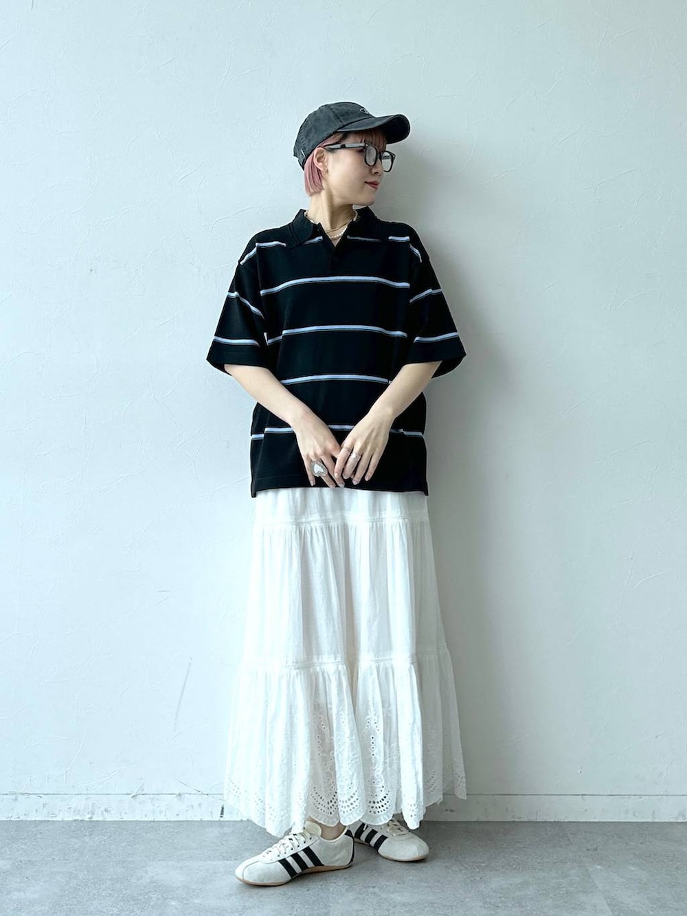 ホワイト系のスニーカー、ブラック系のポロシャツ、ホワイト系のスカートを着用したレディースの春コーディネートの3枚目の写真