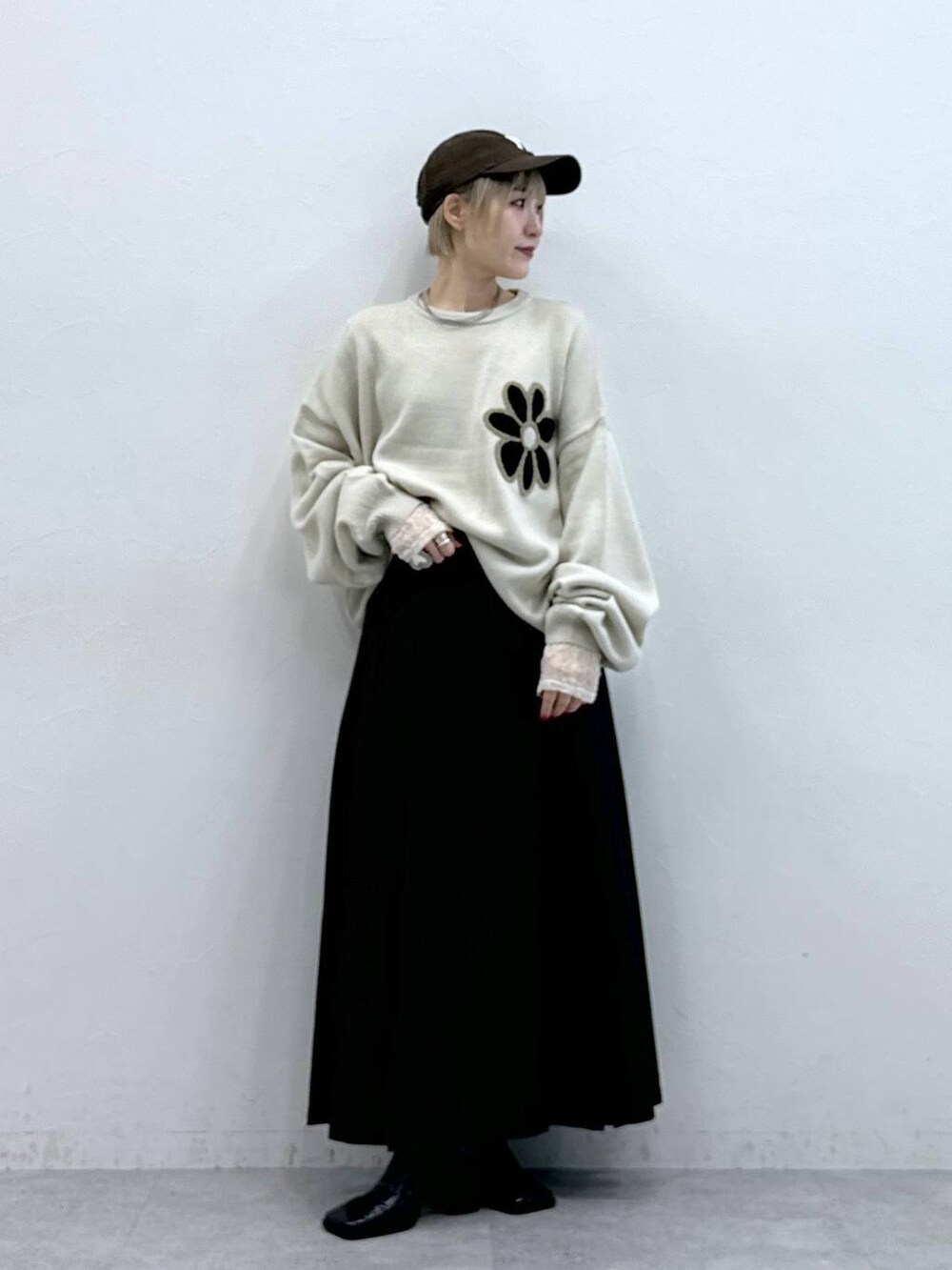 ホワイト系のニット/セーター、ブラウン系のスカート、ホワイト系のTシャツ/カットソーを着用したレディースの秋コーディネートの3枚目の写真