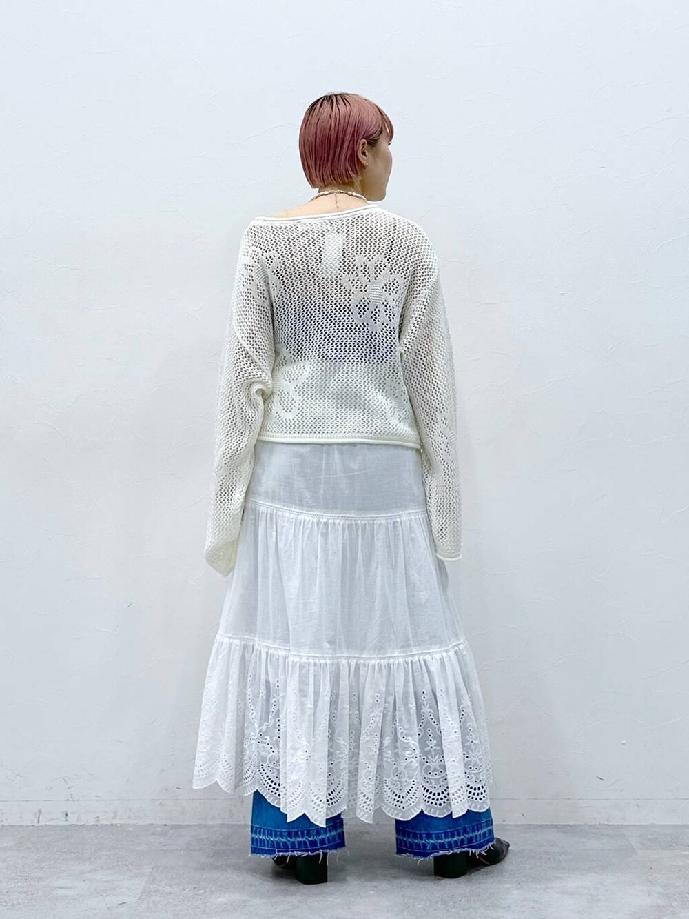 ブルー系のデニムパンツ、ホワイト系のニット/セーター、ホワイト系のスカートを着用したレディースの春コーディネートの7枚目の写真