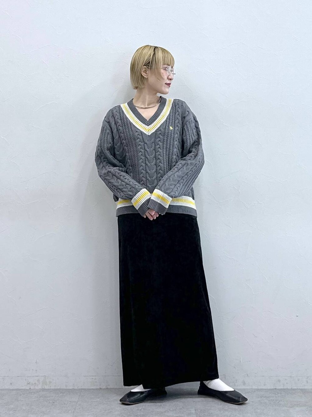 グレー系のニット/セーター、ブラック系のスカートを着用したレディースの秋コーディネートの3枚目の写真