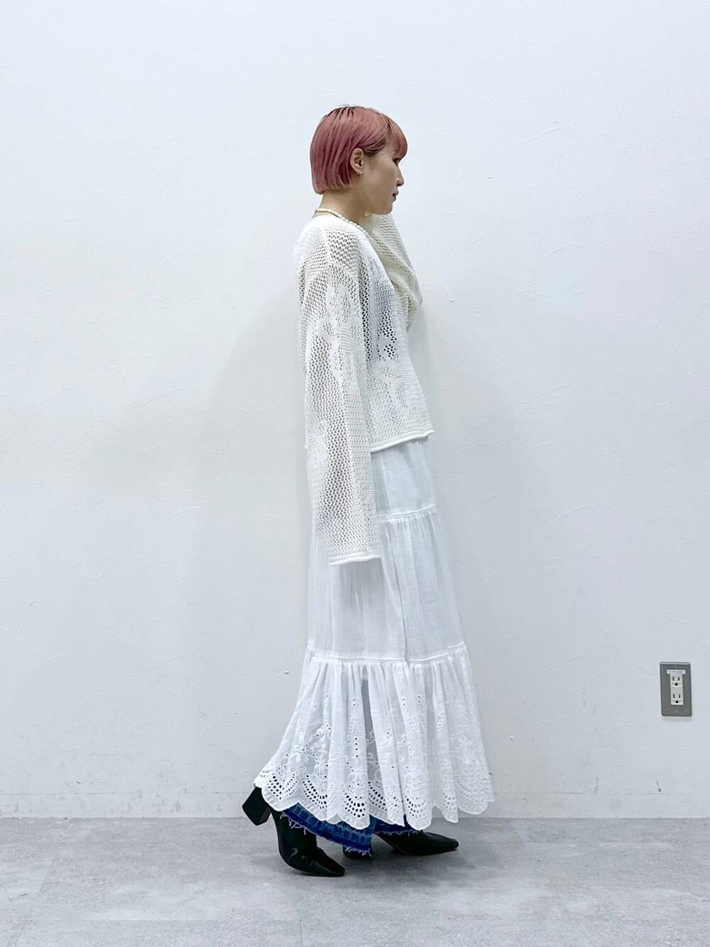 ブルー系のデニムパンツ、ホワイト系のニット/セーター、ホワイト系のスカートを着用したレディースの春コーディネートの6枚目の写真