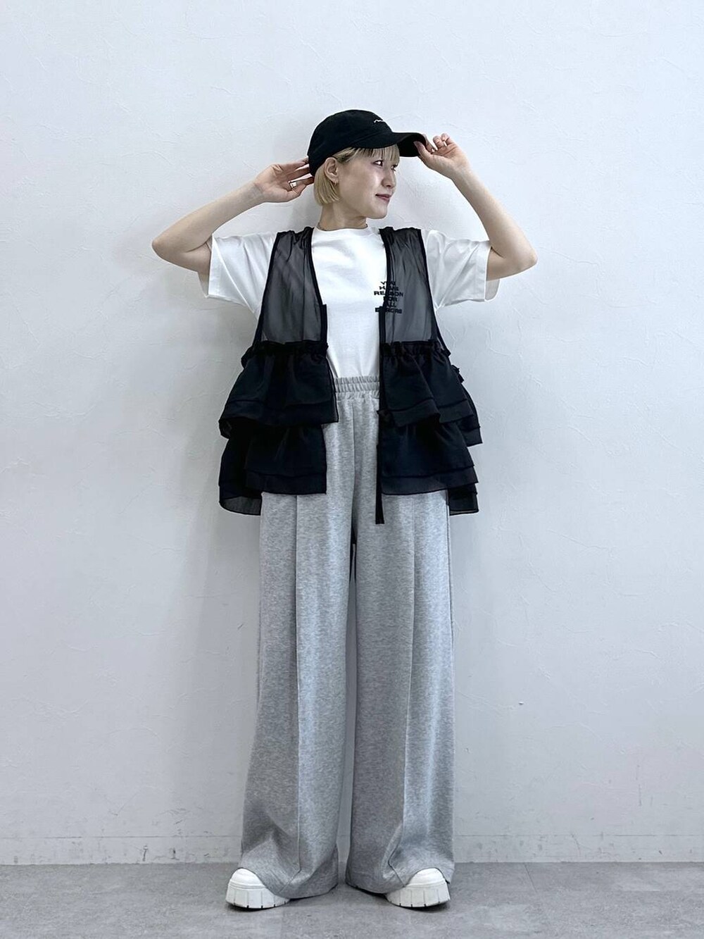 グレー系のスウェットパンツ、ホワイト系のTシャツ/カットソー、ブラック系のベストを着用したレディースの春コーディネートの2枚目の写真