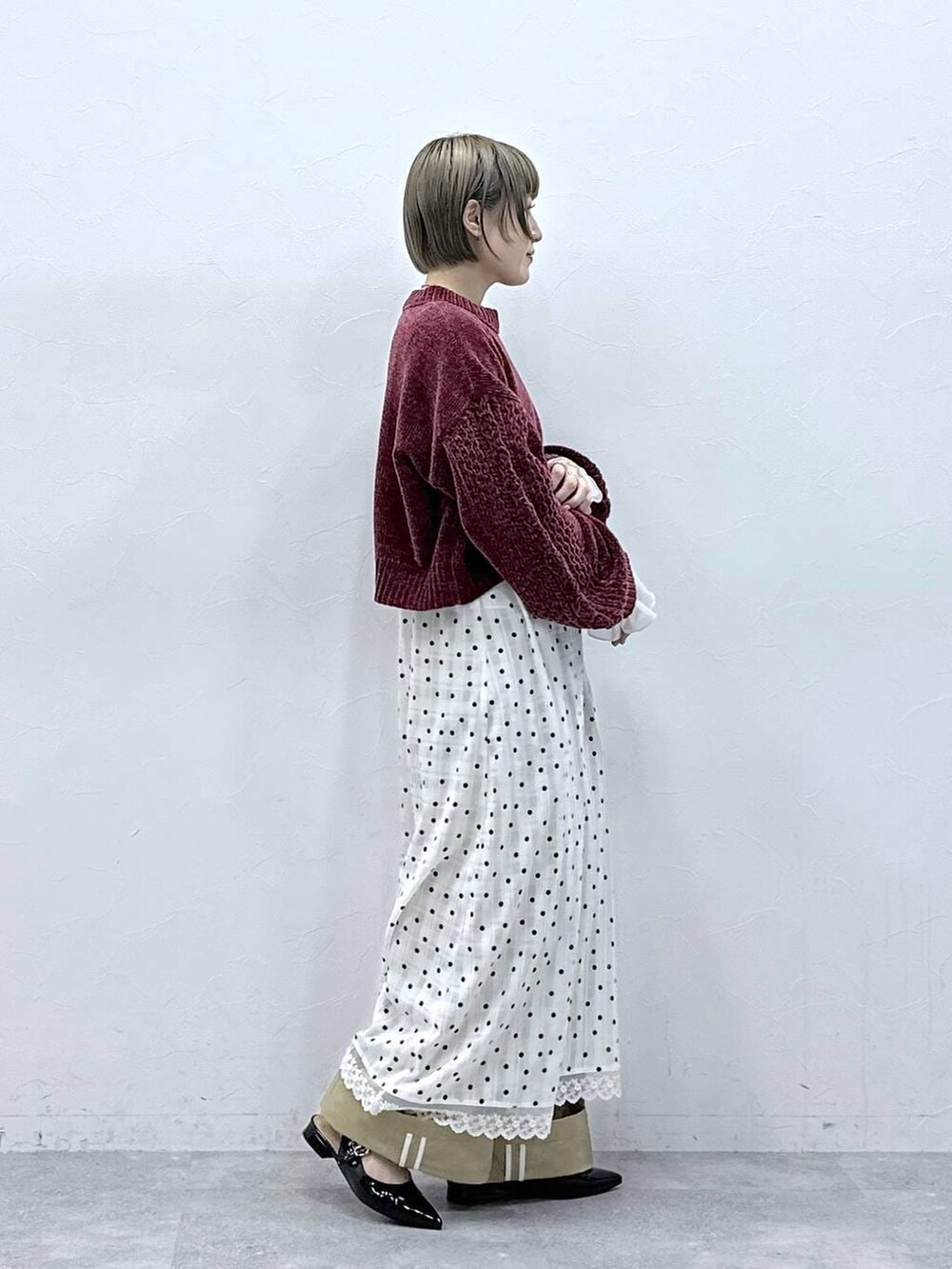 レッド系のニット/セーター、ブラック系のパンプス、ベージュ系のチノパンツを着用したレディースの冬コーディネートの6枚目の写真