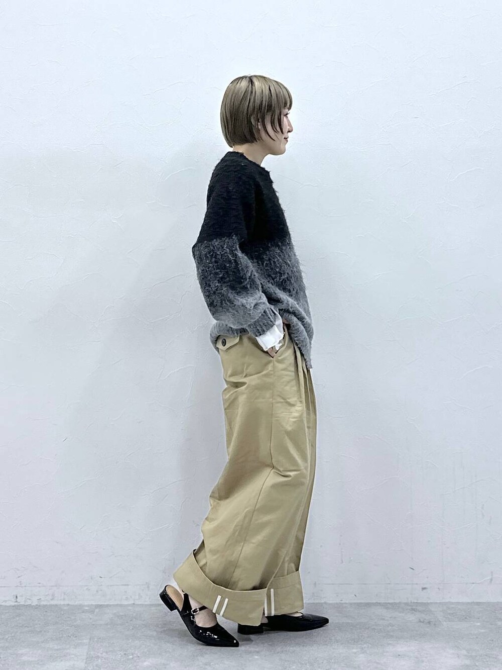 ブラック系のニット/セーター、ブラック系のパンプス、ベージュ系のチノパンツを着用したレディースの冬コーディネートの4枚目の写真