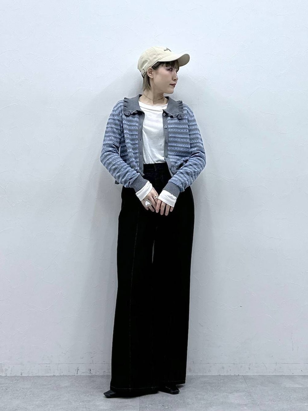 ブラック系のデニムパンツ、ホワイト系のTシャツ/カットソー、グレー系のカーディガン/ボレロを着用したレディースの冬コーディネートの3枚目の写真